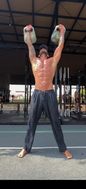 Benjamin pressing two kettlebells overhead